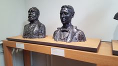 three bronze busturines sitting on top of a wooden shelf