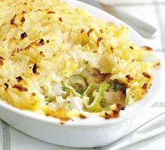 a casserole dish with vegetables and cheese in it on a white table cloth