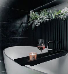 a bath tub sitting next to a candle and some plants in a vase on top of it