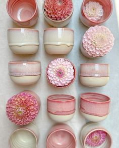 many pink and white bowls with flowers in them