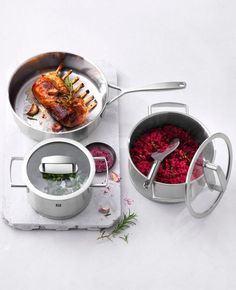 three pots and pans with food in them sitting on a table top next to utensils