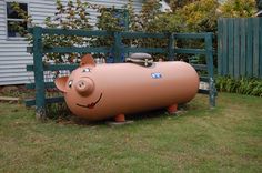 an inflatable pig sitting on top of a lawn next to a blue fence