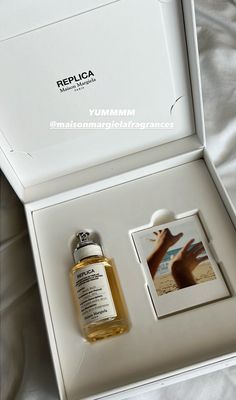 a bottle of perfume sitting in a white box next to a card with an image on it