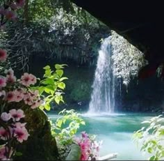 there is a waterfall in the middle of some trees and flowers on the side of the water