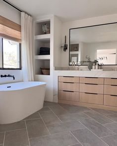 a bathroom with a tub, sink and large mirror on the wall next to it