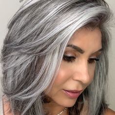 a woman with grey hair wearing a white tank top and silver highlights on her face