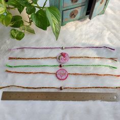 three bracelets and a ruler sitting on a white furnishing next to a potted plant