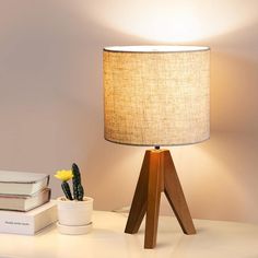 a table with a lamp, books and a cactus sitting on the desk next to it