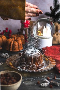 someone sprinkles sugar on a bundt cake in front of other desserts