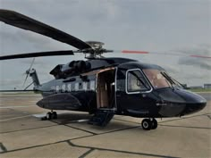 a helicopter sitting on top of an airport tarmac with its door open to the side