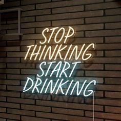 a neon sign that says stop thinking start drinking on the side of a brick wall