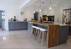 an island in the middle of a kitchen with three bar stools next to it