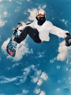 a man flying through the air while riding a snowboard in front of a blue cloudy sky