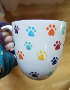 a person holding a coffee cup with colorful paw prints on the outside and inside it