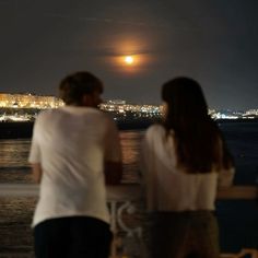 two people looking out over the water at night