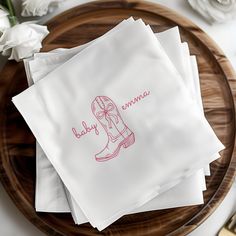 four napkins with pink ink on them sitting on a wooden plate next to flowers