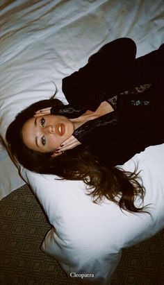 a woman laying on top of a white pillow