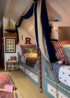 a bed with red, white and blue sheets in a room next to a rug