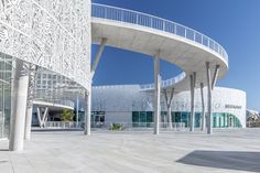 the building is white and has many columns on each side, along with glass windows