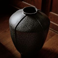 a black vase sitting on top of a wooden floor