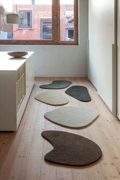 four rugs are arranged on the floor in front of an open window, near a kitchen counter