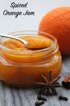 an orange jam in a glass jar with star anise and cinnamon on the side