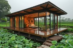 a small wooden house sitting in the middle of a lush green field with water lilies