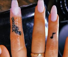 two fingers with tattoos on them and one has a music note tattooed on the middle finger