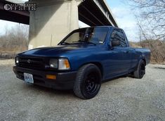 a blue pick up truck parked under a bridge