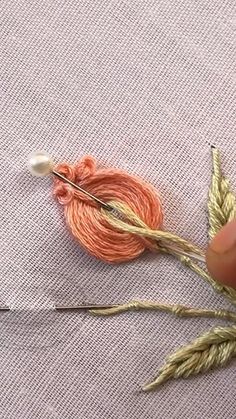 someone is working with some yarn and needles on a piece of fabric that has been stitched together