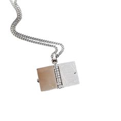 a silver necklace with a small square pendant hanging from it's side on a white background