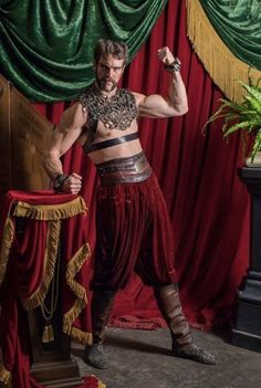 a man in costume standing next to a red curtain