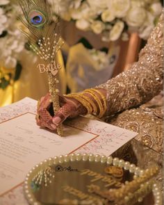 a peacock feather on top of a table next to a wedding card and ring bearer