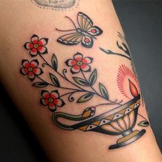 a woman's arm with flowers and butterflies on it, while she is wearing a tattoo