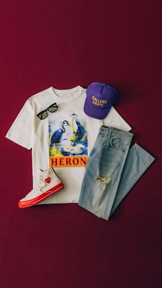 a t - shirt, jeans and hat are laid out on a red surface