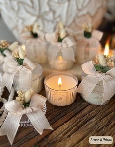 small candles with bows on them are sitting on a table next to some other decorations