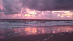 the sun is setting over the ocean with clouds in the sky and water on the beach