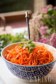 a blue and white bowl filled with shredded carrots