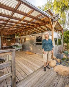 a woman standing on a wooden deck in front of an airstream that is built into the ground