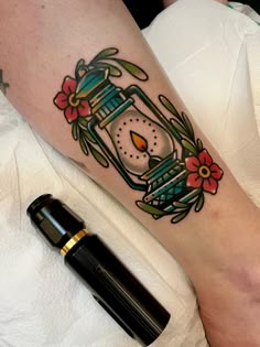 a woman's leg with a tattoo on it that has a clock and flowers