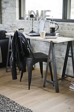 a room with a desk, chair and laptop on the table in front of a window