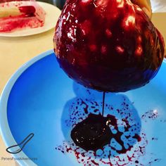 a blue plate topped with an apple covered in chocolate