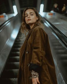 a woman standing on an escalator with her hand in her pocket