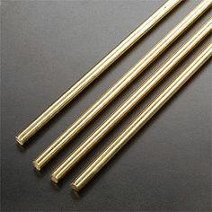 four brass rods on a black surface