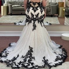 a woman is standing in front of a mirror wearing a black and white wedding dress