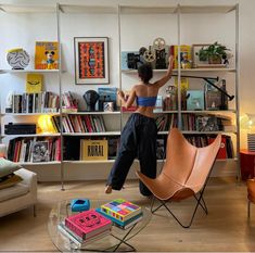 a woman standing on top of a chair in front of a book shelf filled with books