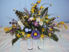 a bunch of flowers that are sitting on a bed with two black hooks in front of them