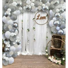 the balloon arch is decorated with white and silver balloons, greenery and love sign