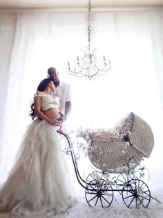 a man and woman standing next to a baby carriage in front of a chandelier