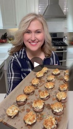 a woman holding a tray full of food in front of her face and smiling at the camera